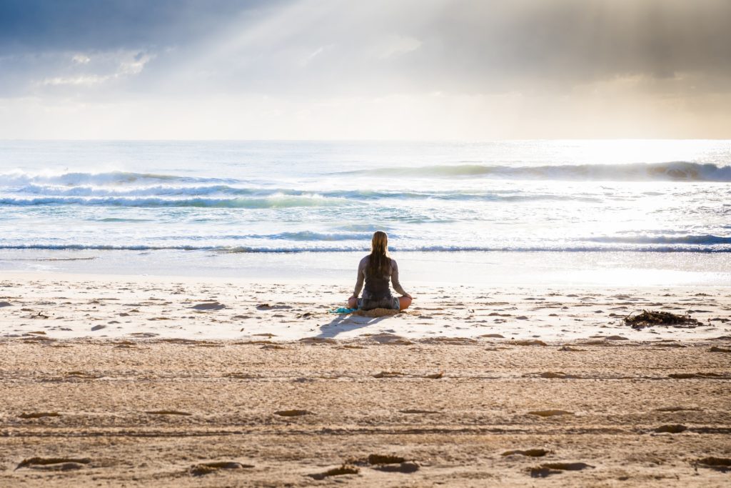 девушка медитирующая  на берегу моря в позе лотоса